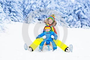 Mother and baby on sleigh ride. Winter snow fun.