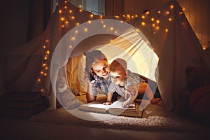 Mother and baby son with a book and a flashlight before going to