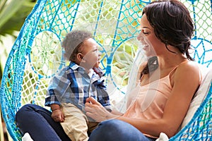 Mother With Baby Son Relaxing On Outdoor Garden Swing Seat