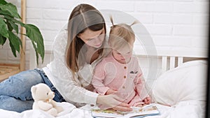 Mother and baby sonreading a book in bed before going to sleep. Family love time together