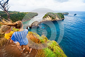 Mother, baby stand at high cliff, look at sea view