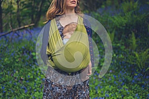 Mother with baby standing in meadow of bluebells