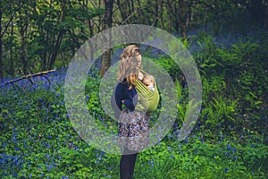 Mother with baby standing in meadow of bluebells