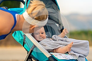 Mother with baby in stroller enjoying motherhood at sunset lands