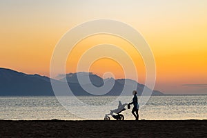 Mother with baby stroller enjoying motherhood at sunset landscape