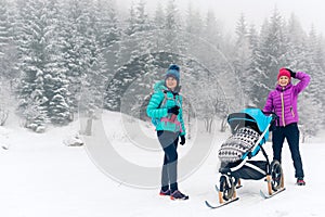 Mother with baby stroller enjoying motherhood in winter forest