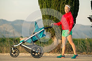 Mother with baby stroller enjoying summer sunset landscape