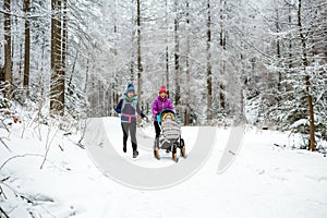 Mother with baby stroller enjoying winter in forest, family time