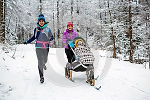 Mother with baby stroller enjoying winter in forest, family time