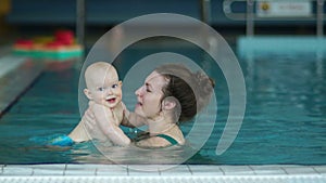 Mother and baby swim in the pool, have fun and laugh. Accelerated video playback, healthy lifestyle of babies