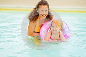 Mother and baby with swim ring swimming in pool