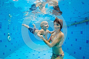 Mother with baby swimming, diving underwater in pool