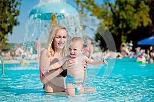 Mother and baby in swimming pool. Parent and child swim in a tropical resort. Summer outdoor activity for family with kids.