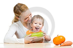 Mother with baby at table. Boy holding zucchini