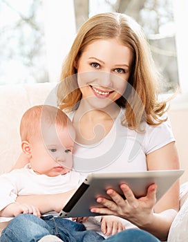 Mother and baby with tablet computer on the couch at home