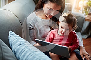 Mother, baby and tablet on sofa watching educational video online on streaming service in home. Love, family time and