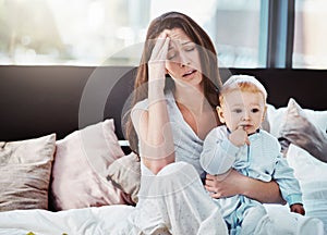 Mother, baby and tired or stress in a home bedroom or bed with postpartum, headache or anxiety. Depression, mental
