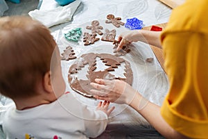 Mother and baby together cut out cookies from the dough. Top view from the shoulder. Christmas concept and family