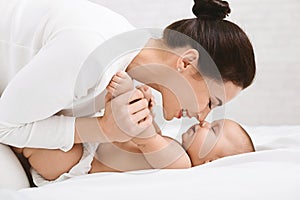 Mother and baby touching noses in bed