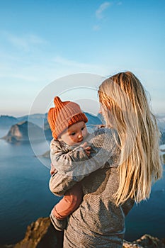 Mother with baby traveling together family vacations in Norway woman with infant child in mountains