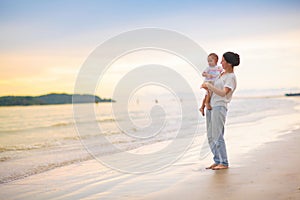 Mother and baby on tropical beach at sunset