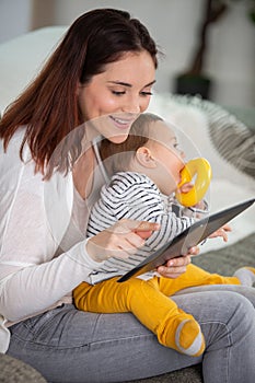 mother with baby using digital tablet at home