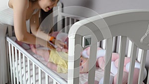 A mother with a baby waking up in a crib.