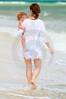 Mother and baby walking along beach