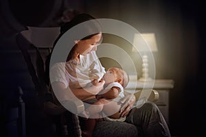 Mother and baby in white bedroom. Asian mom