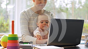 Mother with baby working on laptop at home office