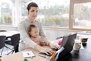 Mother with baby working on laptop at home office