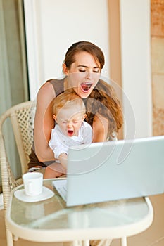 Mother and baby yawing while working on laptop photo