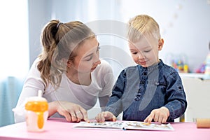 Mother or babysitter reading a book to kid. Indoors