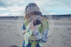 Mother on beach putting her baby in wrap