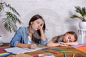 Mother becoming frustrated with daughter whilst doing homework sitting at the table at home in learning difficulties