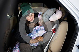 Mother belt child safety seat chair with baby girl is on back seat of car