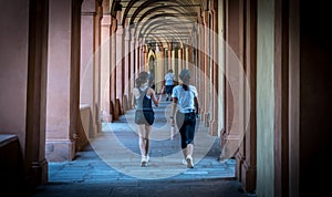 Mother in black hat and daughter in shorts walking down promanade in sneakers and shorts and pants