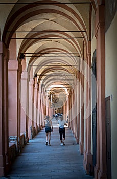 Mother in black hat and daughter in shorts walking down promanade in sneakers and shorts and pants