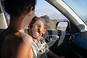 Mother with black little girl in car while they going on vacation