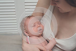 Mother with a blond sleeping baby in her arms, a moment of tenderness. Close-up