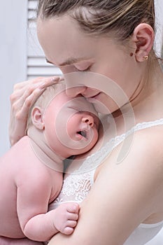 Mother with a blond sleeping baby in her arms, a moment of tenderness. Close-up