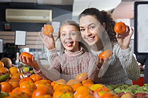 Mother and blonde daughter buying mandarins in shop