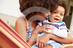 Mother bonding with young son sitting in a hammock photo