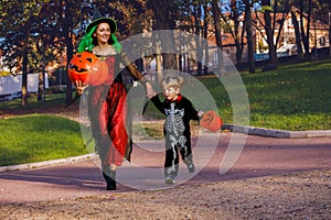 Mother and boy run in costumes of skeleton, witch holding bucket