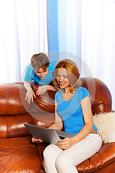 Mother and boy watching at laptop screen on sofa