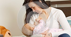 Mother breast feeding her baby on bed