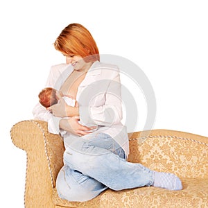 Mother breast-feeding newborn baby on the sofa