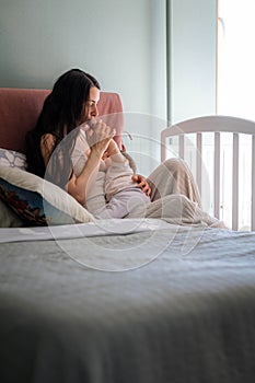 Mother breastfeeding baby in her arms at home, beautiful mom breast feeding her toddler child, baby eating mother milk