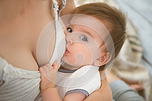 Mother breastfeeding baby in her arms at home. Mom breast feeding her newborn child. Baby eating mother`s milk. Concept