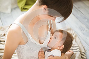 Mother breastfeeding baby in her arms at home. Mom breast feeding her newborn child. Baby eating mother`s milk. Concept of lactat